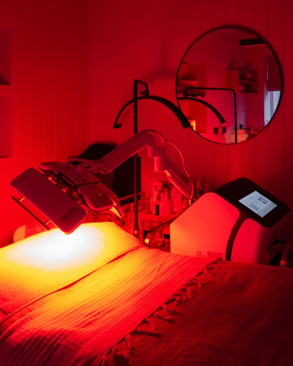 Dermalux LED light therapy glowing red over a treatment couch